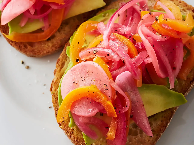 Pickled red onions on top of toast with avocado and other veggies