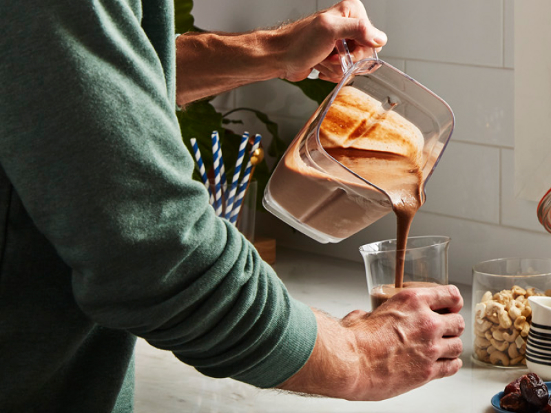 Person pouring protein shake into a glass