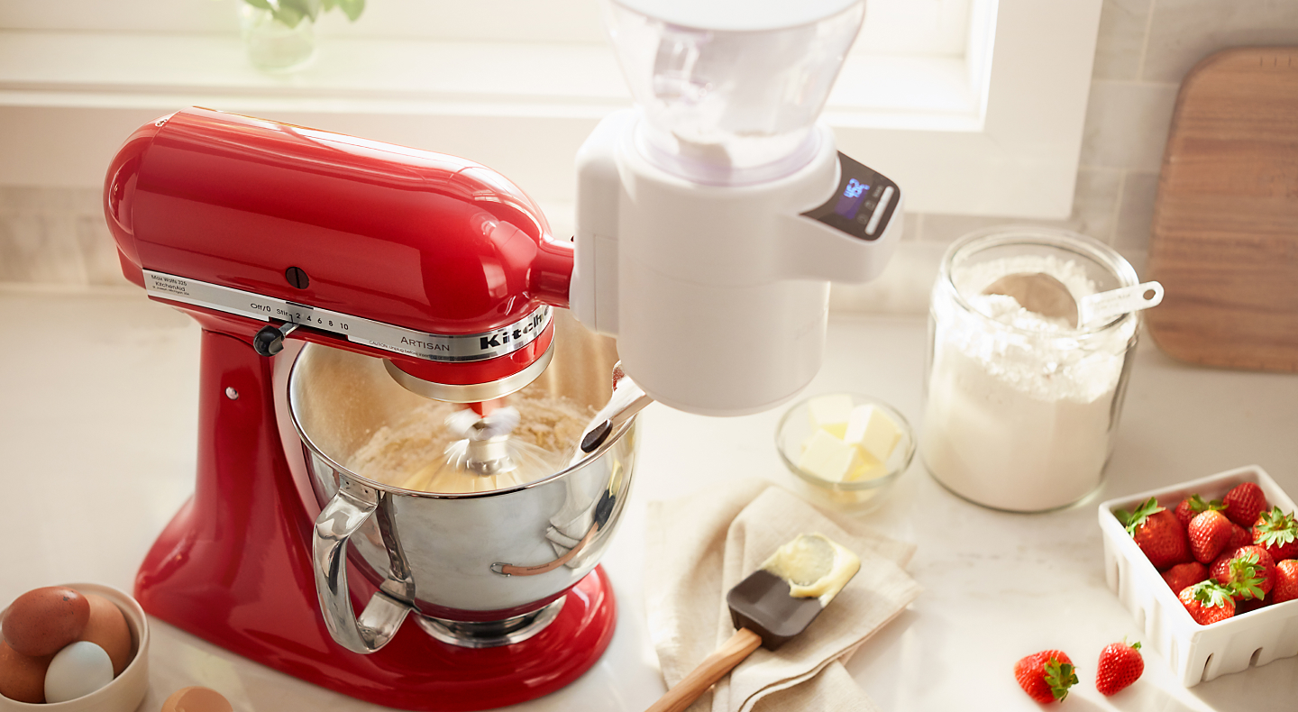 A red KitchenAid® stand mixer amongst various baking ingredients