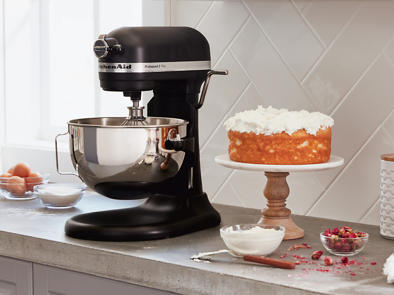 A black KitchenAid® stand mixer next to a cake