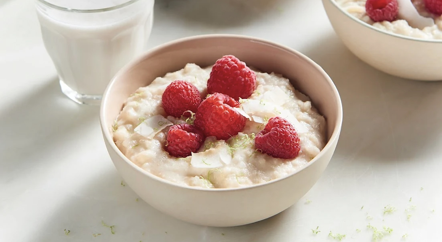 A bowl of rice pudding topped with raspberries