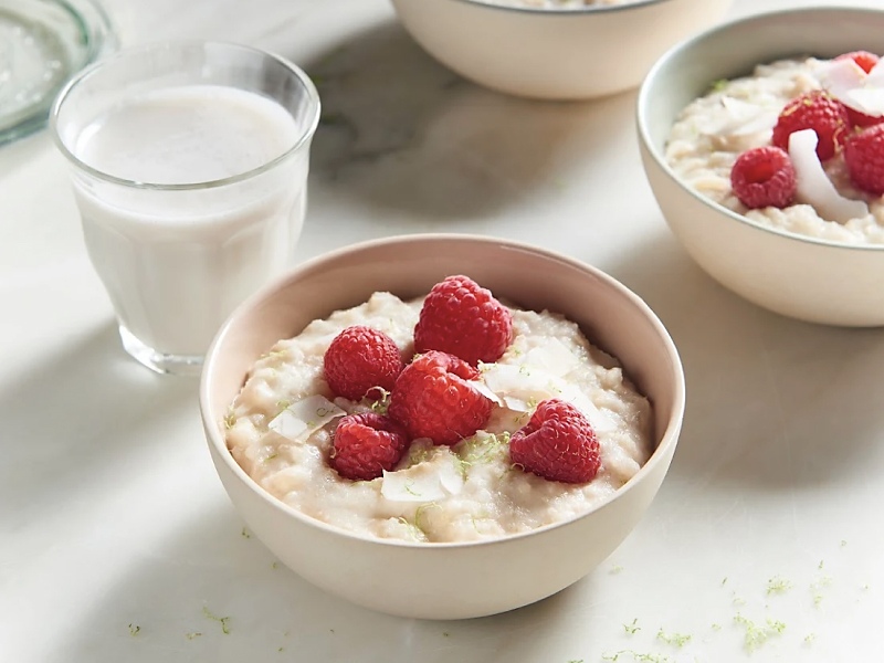 A bowl of rice pudding topped with raspberries