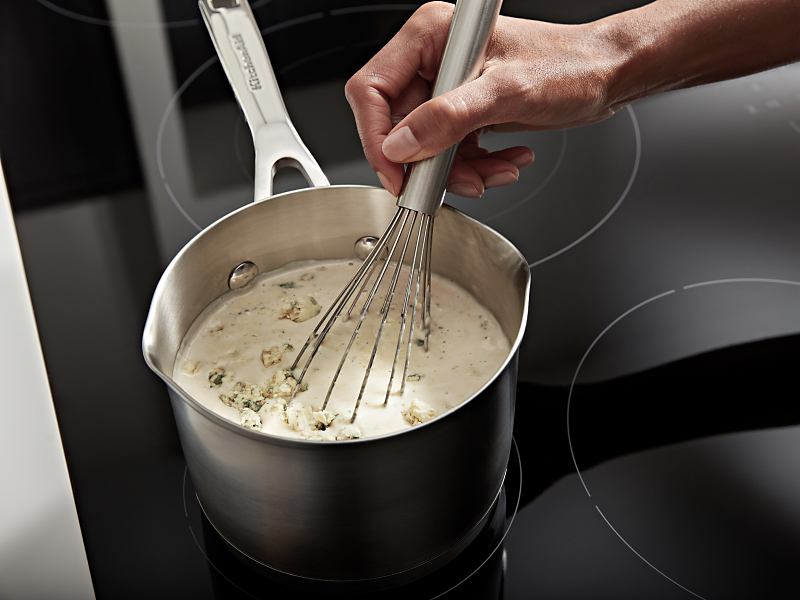 A hand whisking rice and heavy cream