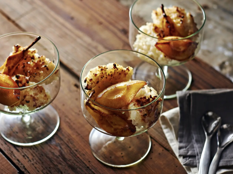 Rice pudding with caramelized pears in glass dessert bowls. 