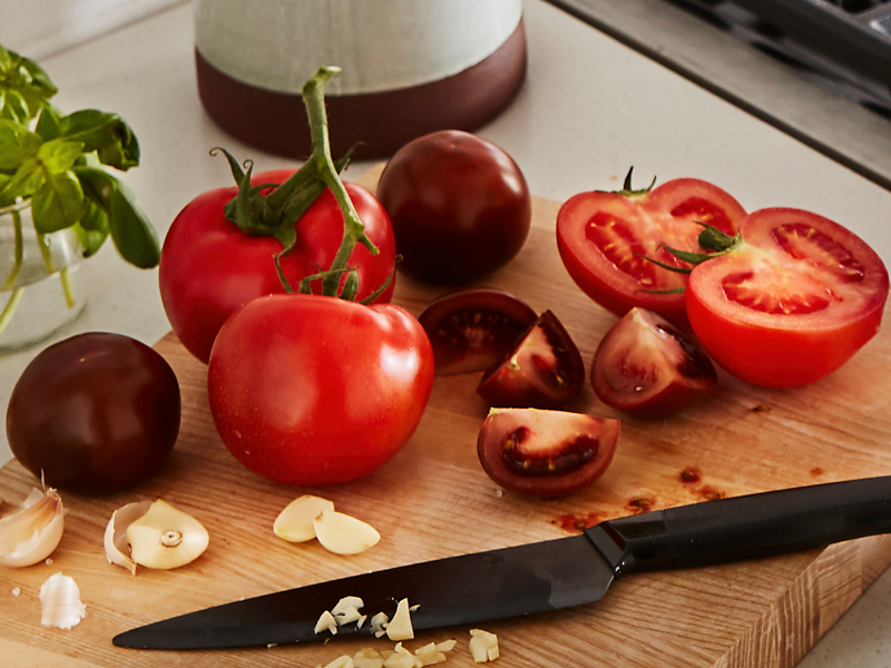 A cutting board piled with tomatoes