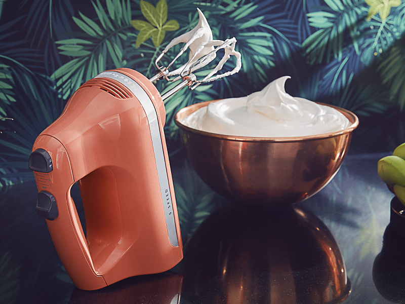 Orange KitchenAid® hand mixer next to a bowl of whipped cream