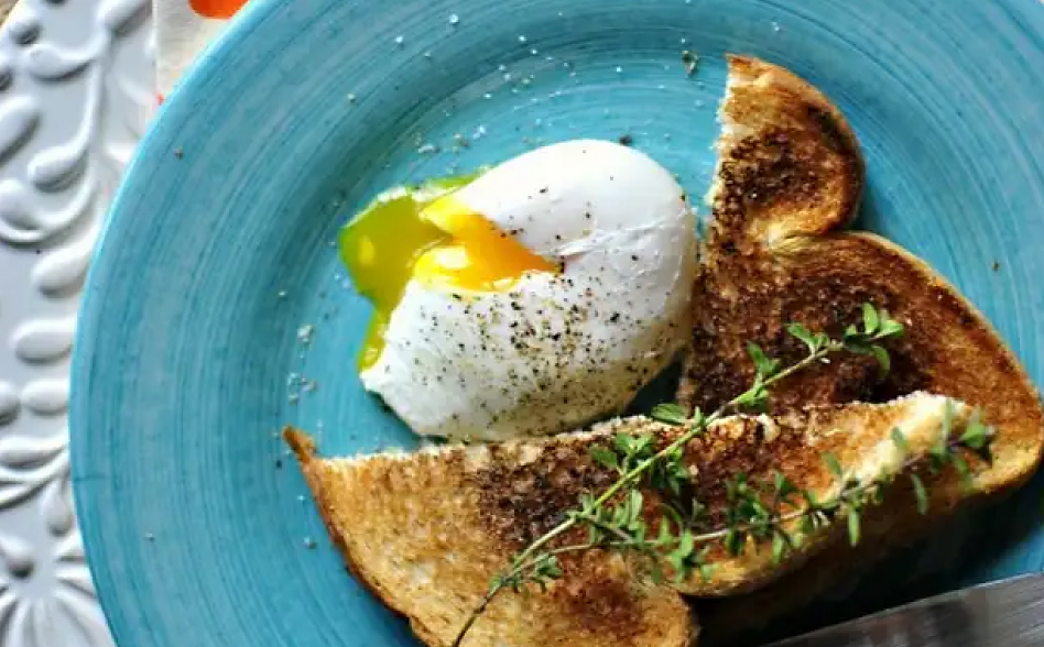 Close up of poached egg with toast on blue plate