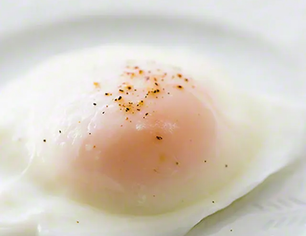 Close up of poached egg with grains of salt and pepper on top