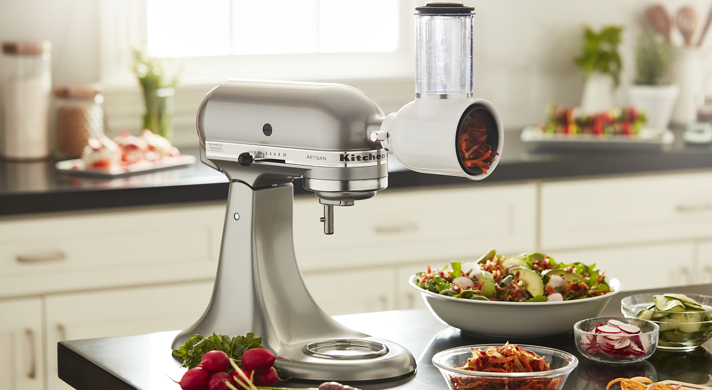 KitchenAid® stand mixer with a fresh prep slicer/shredder attachment in a modern kitchen next to freshly sliced vegetables