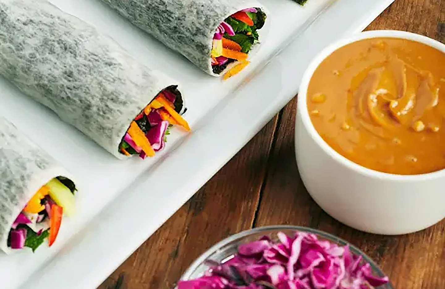 Rainbow spring rolls with shredded cabbage and peanut dipping sauce