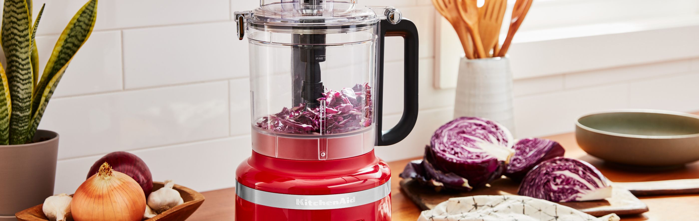 KitchenAid® food processor on a kitchen counter next to sliced purple cabbage and other vegetables