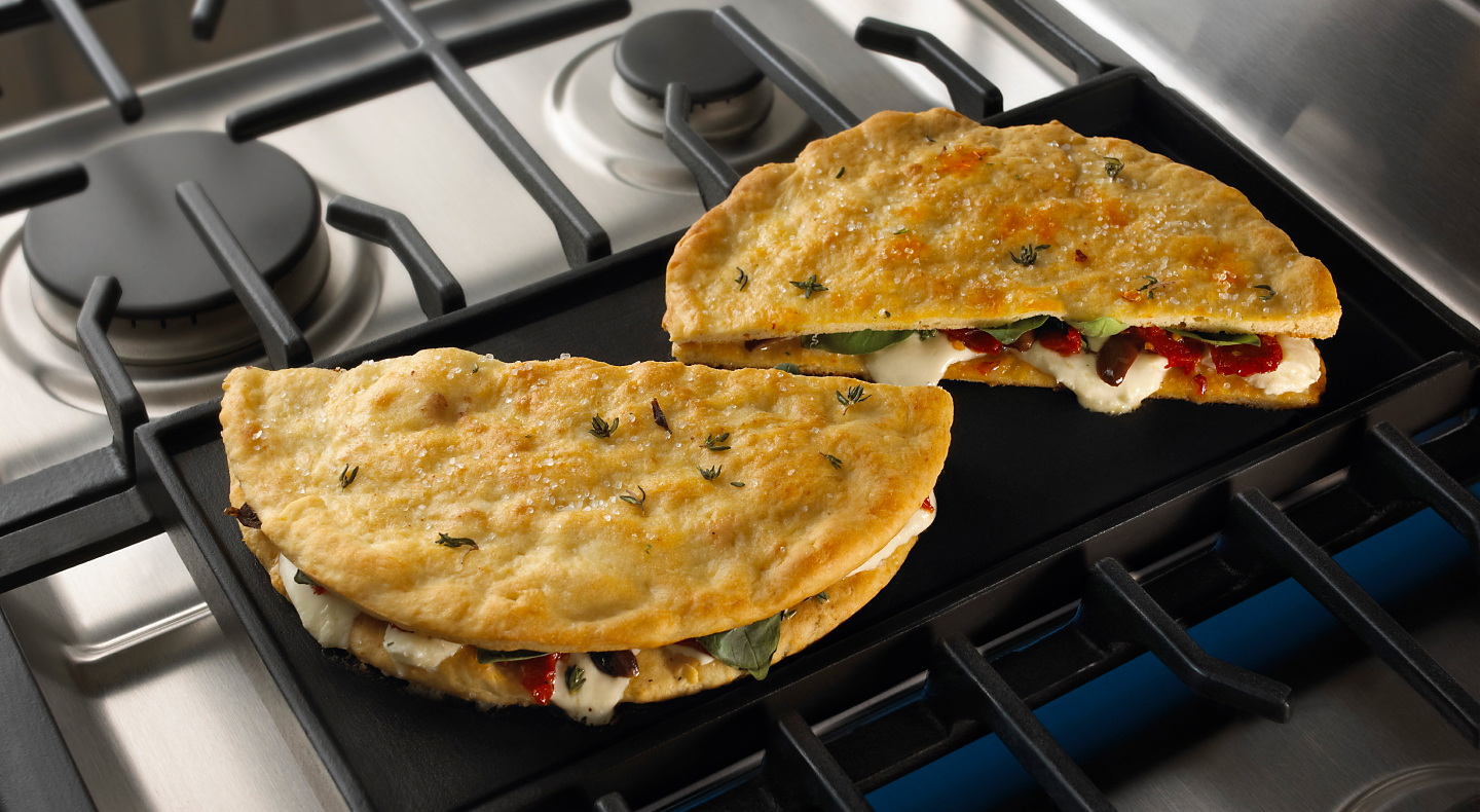 Stuffed pita breads cooking on a gas stove griddle