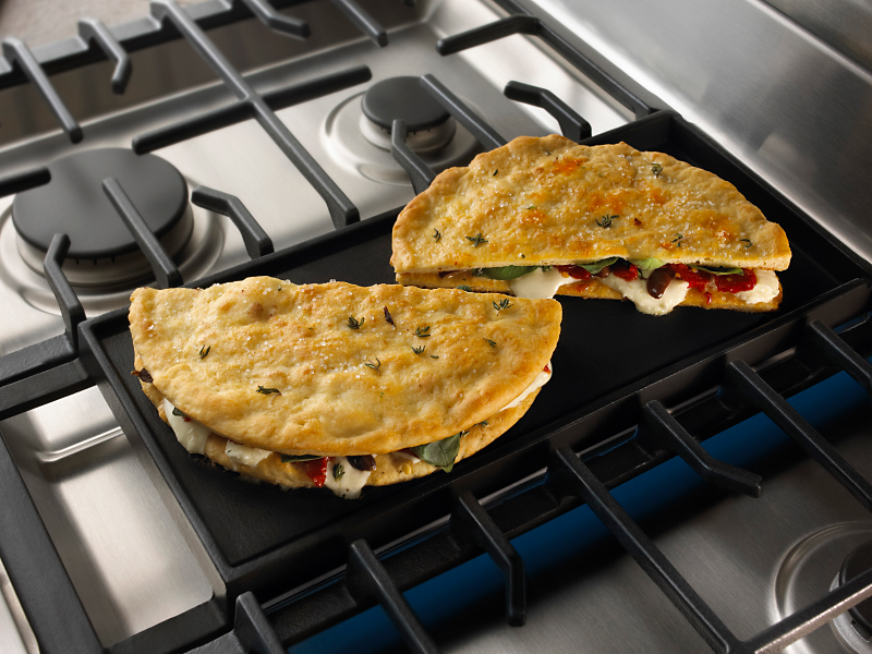 Stuffed pita breads cooking on a gas stove griddle