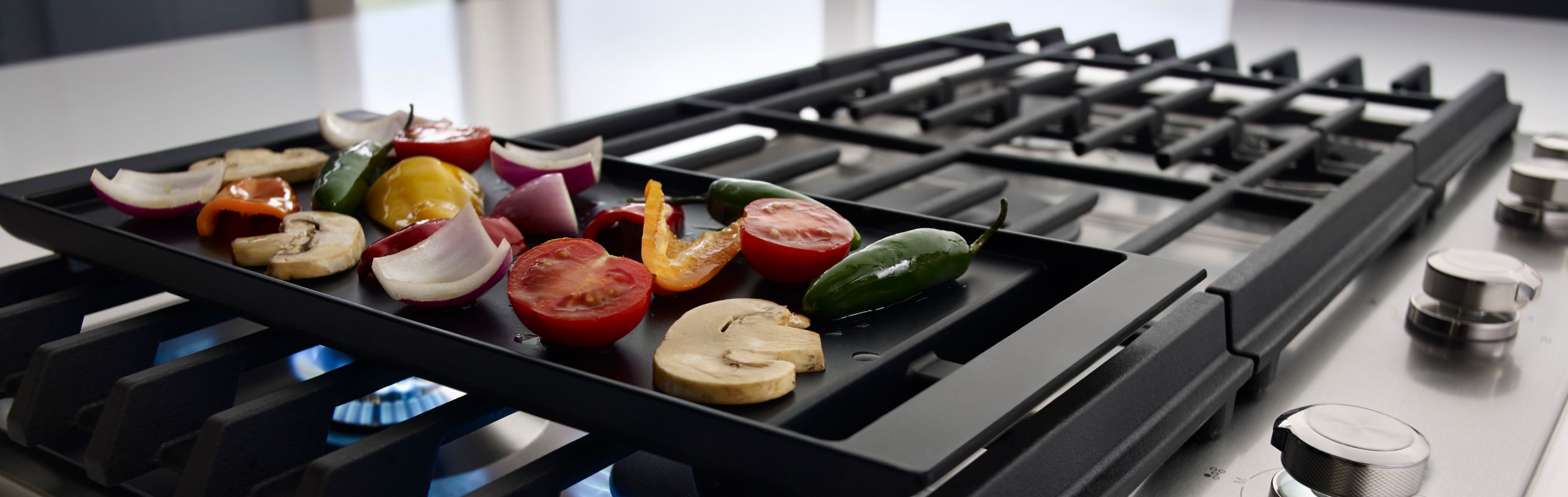 Vegetables cooking on a gas stove griddle
