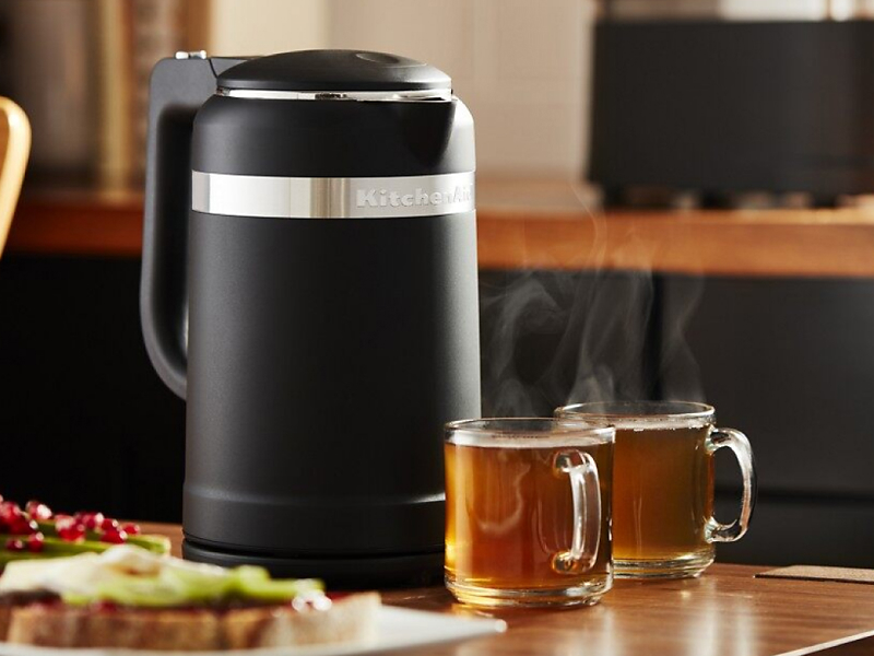 Black KitchenAid® electric tea kettle on table with glasses of tea. 