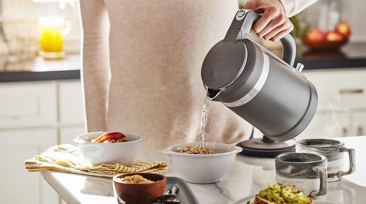Woman pouring water on oatmeal with an electric kettle