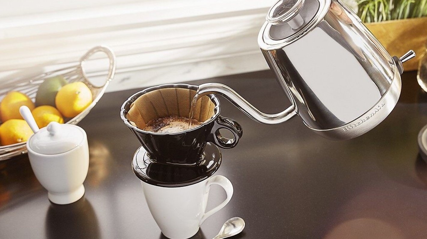 Hand pouring gooseneck electric kettle over a pour over cone filled with coffee Hand pouring gooseneck electric kettle over a pour over cone filled with coffee