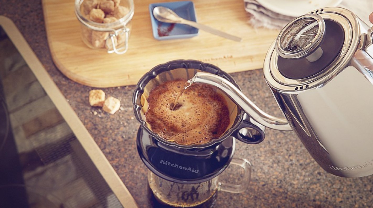 Hand pouring water from gooseneck electric kettle to make pour over coffee Hand pouring water from gooseneck electric kettle to make pour over coffee
