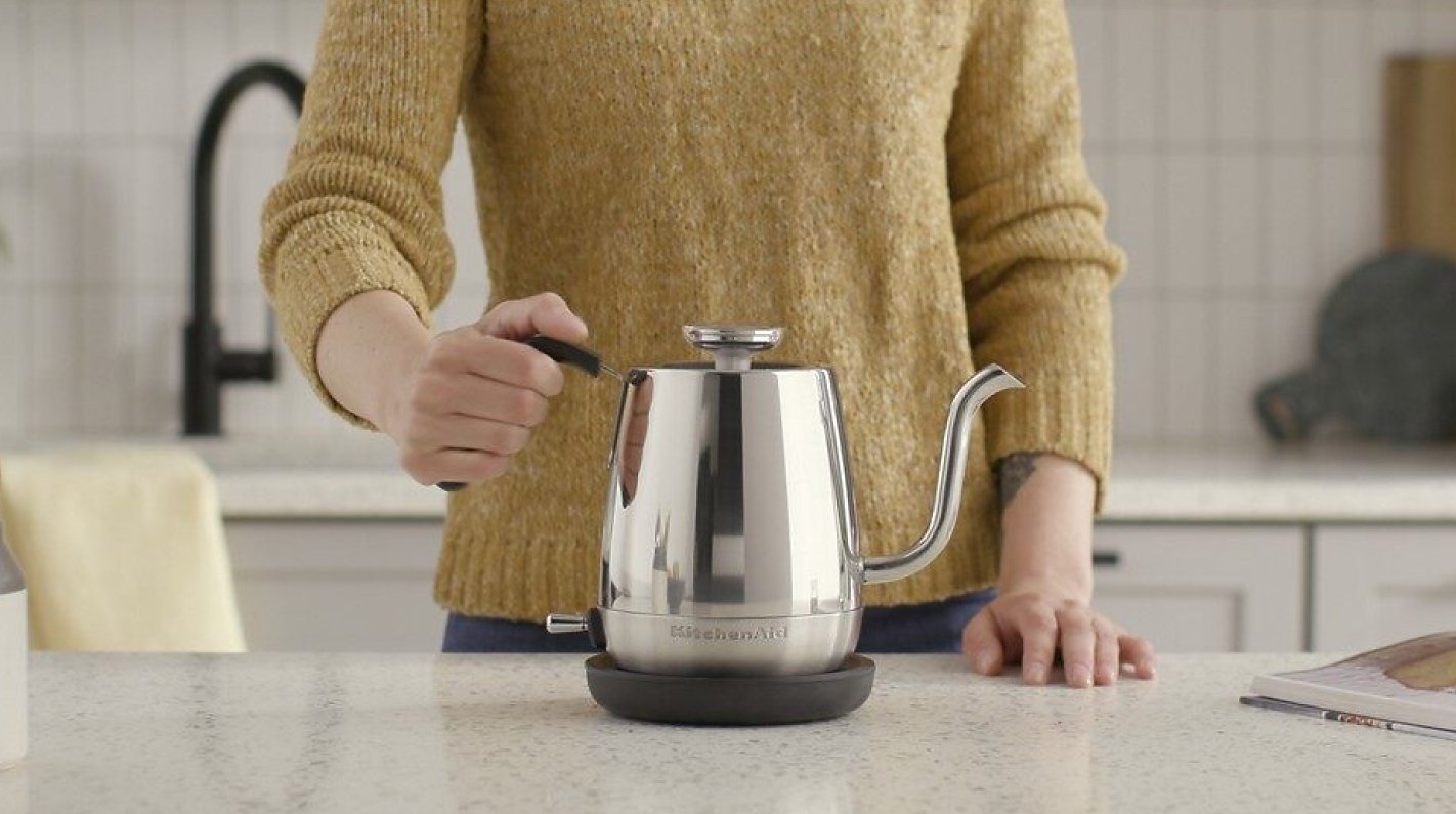 Woman picking up an electric gooseneck kettle Woman picking up an electric gooseneck kettle
