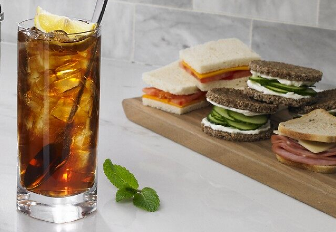 Glass of iced tea next to sandwiches
