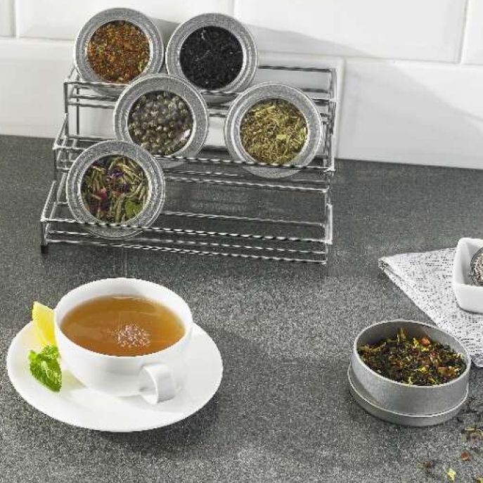 Cup of tea on counter with containers of loose leaf tea