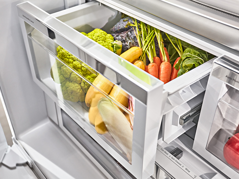 Assorted vegetables inside an open refrigerator crisper drawer