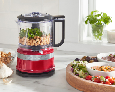 Red food chopper on counter filled with chickpeas and herbs