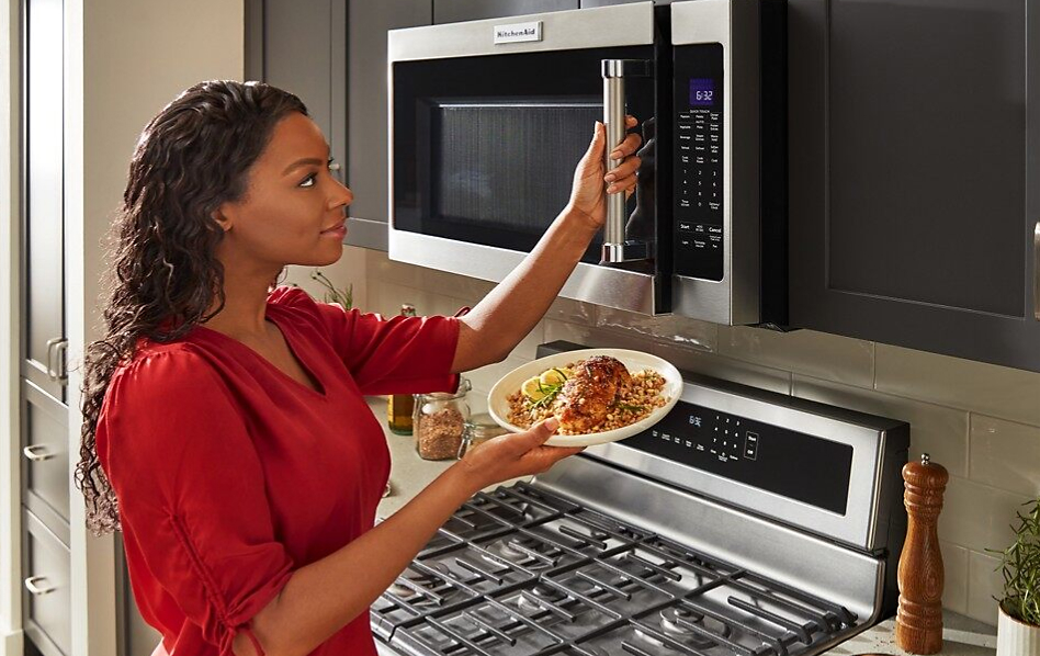 Woman about to place food in a KitchenAid® Over-the-Range Microwave