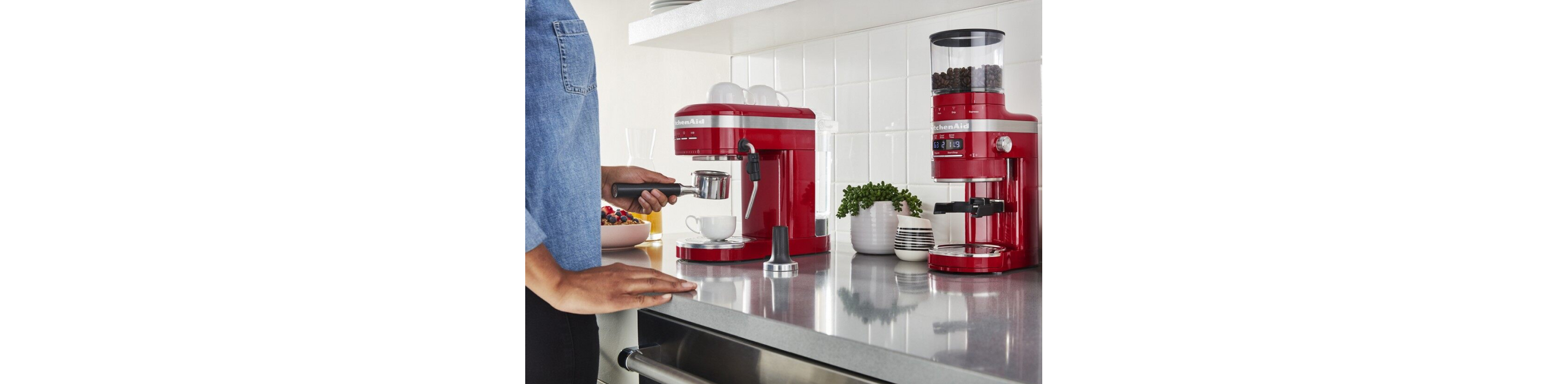 Woman using a red espresso coffee maker and grinder on countertop