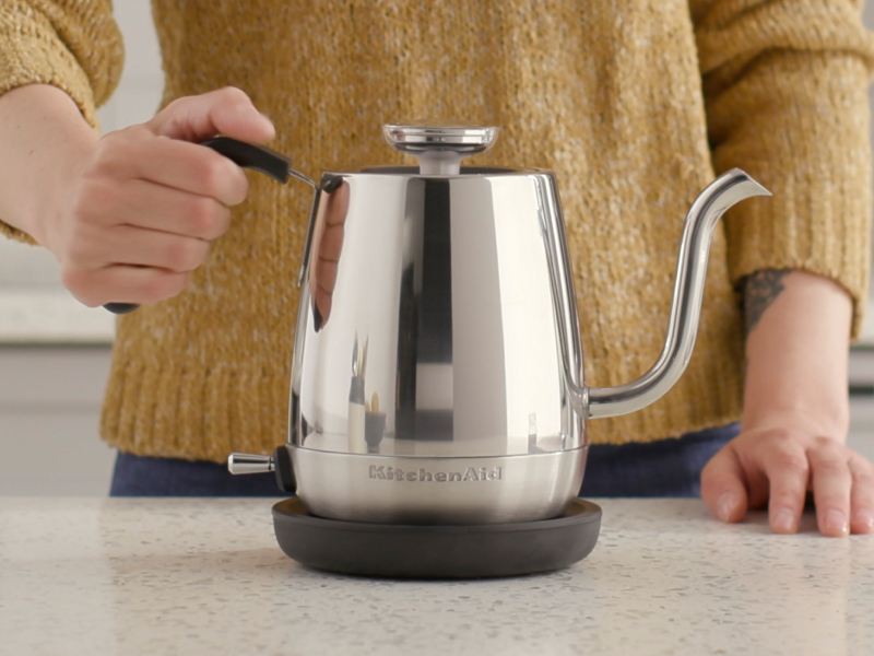 Maker holding on to handle for silver KitchenAid® gooseneck electric kettle