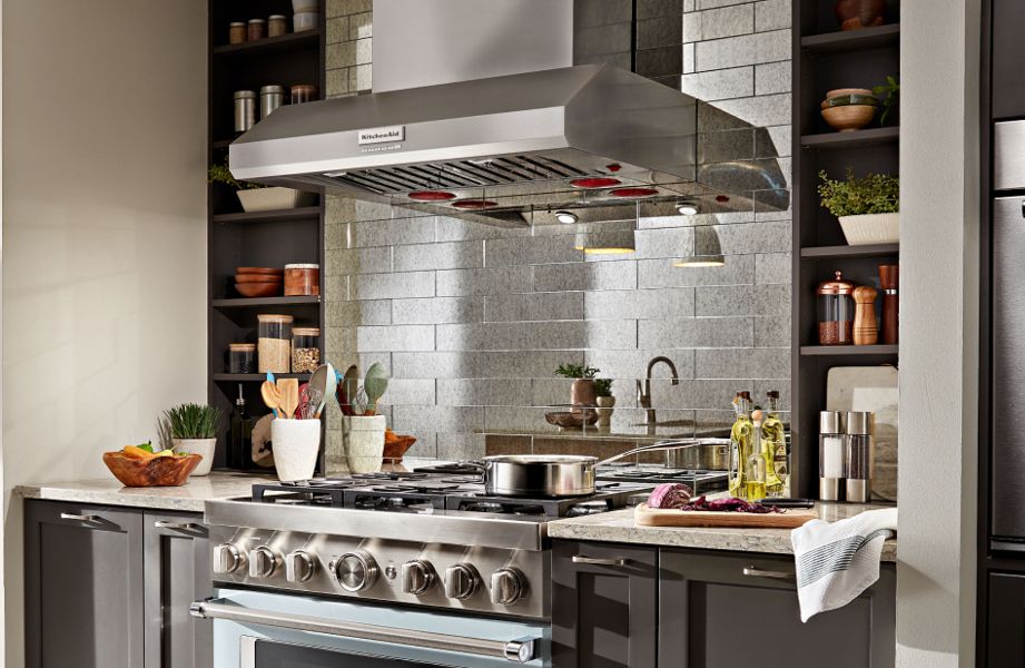 Wall-mount commercial-style KitchenAid® hood above KitchenAid® gas range with animated overlay of height, width and depth markers