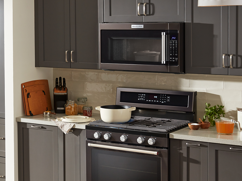 KitchenAid® over-the-range microwave and gas range in brown-gray cabinetry