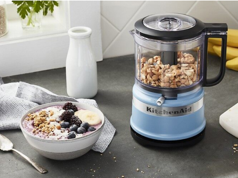Blue food processor filled with nuts