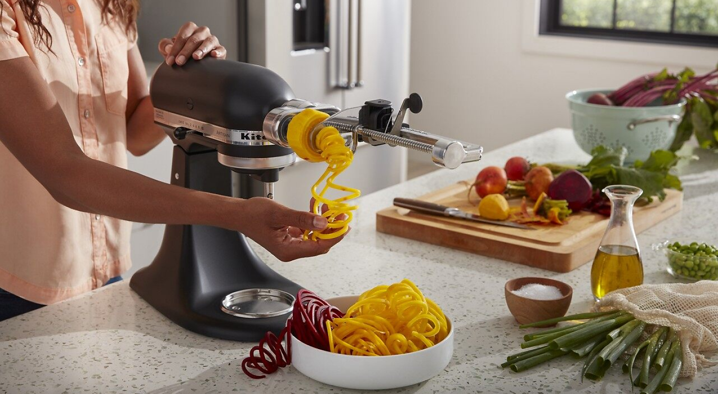 Woman spiralizing vegetables with KitchenAid® stand mixer