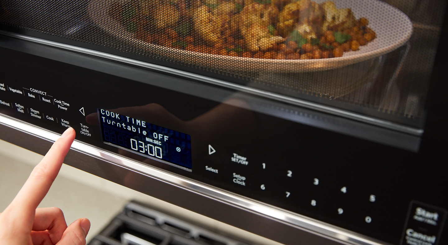 A person programming a setting on a KitchenAid® microwave.