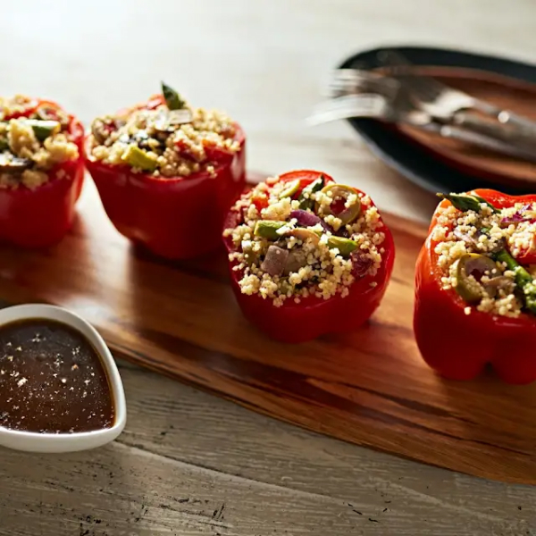 Stuffed red peppers on a wood serving board.