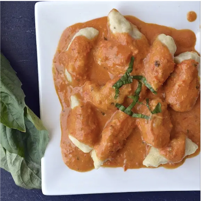 A plate of chicken covered in fresh tomato vodka sauce