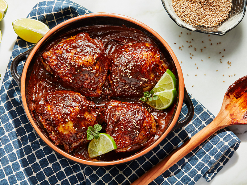 Chicken sitting in barbeque sauce marinade surrounded by lime wedges