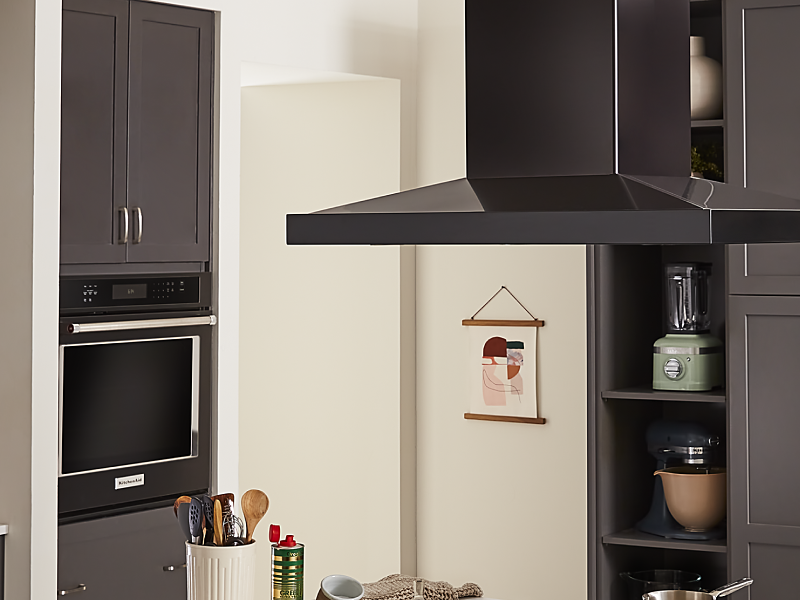 A vent hood and a single wall oven in a kitchen
