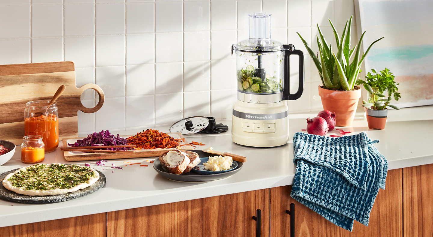 A KitchenAid® food processor with fresh vegetables in a modern kitchen.