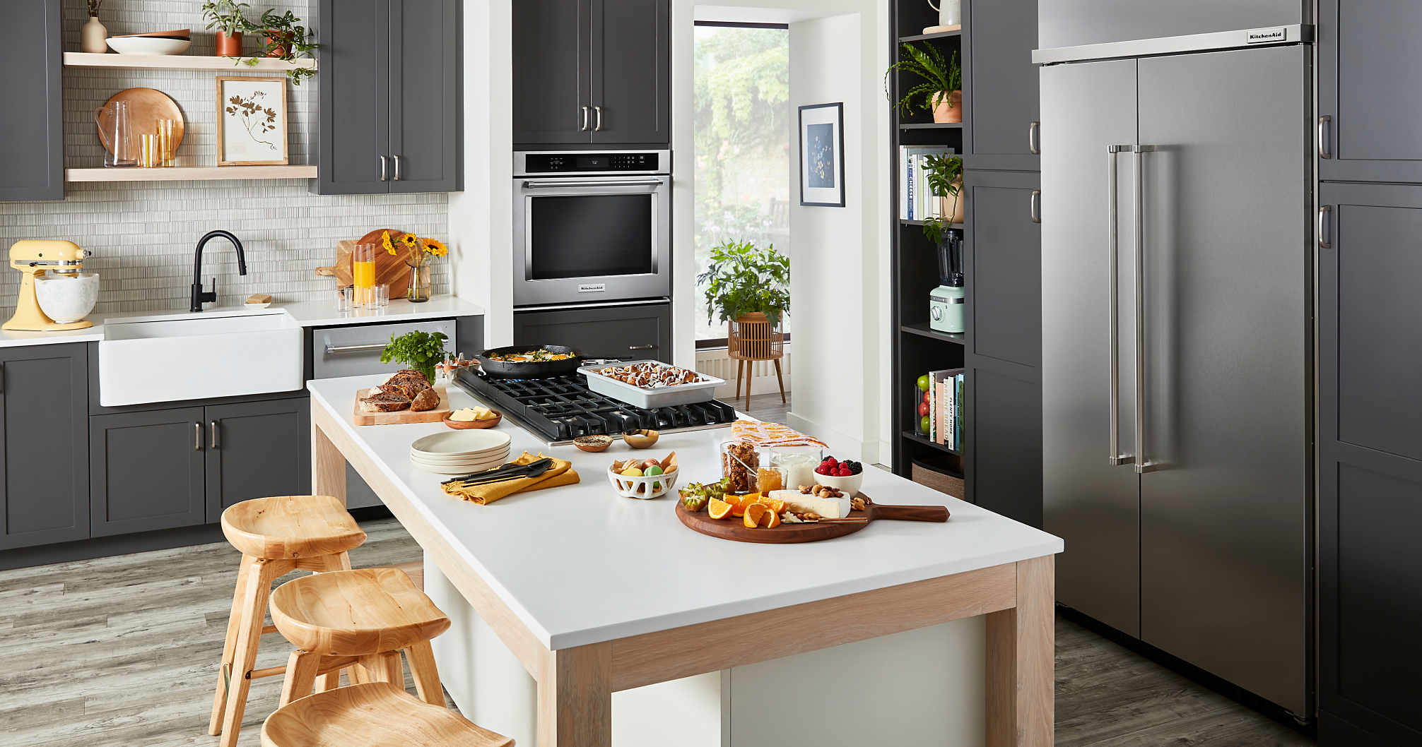A stylish, modern kitchen filled with KitchenAid® appliances and prepared dishes on the island.
