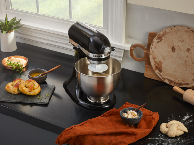 Black KitchenAid® stand mixer on black countertop next to homemade pretzels