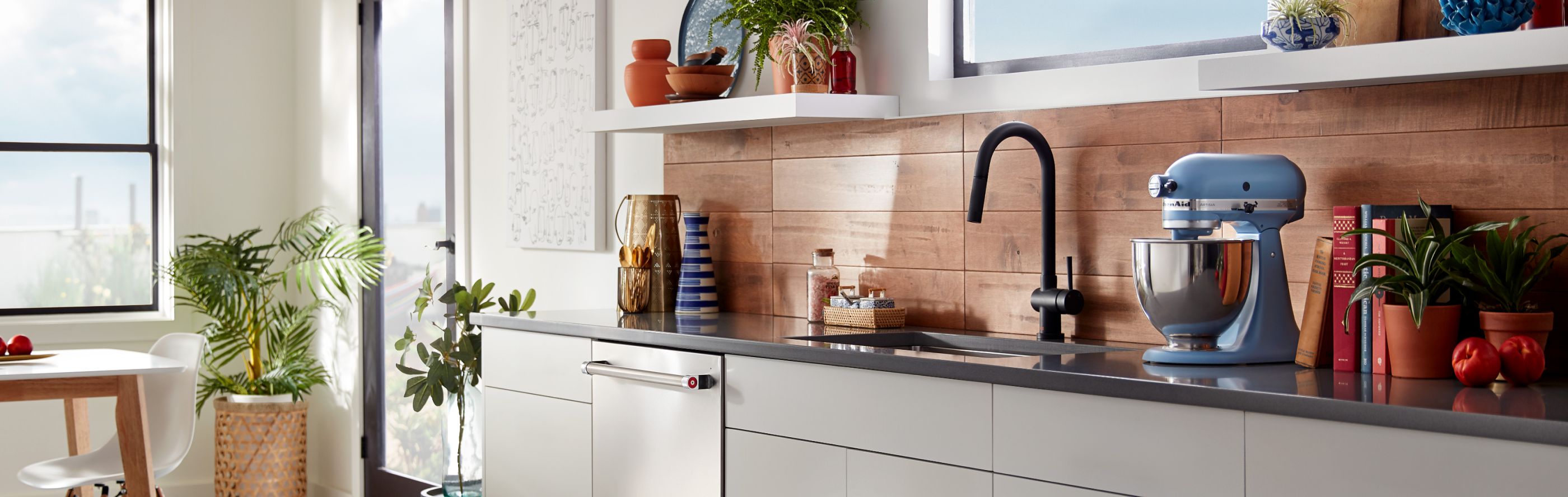 Blue KitchenAid® stand mixer on countertop with wood panel backsplash