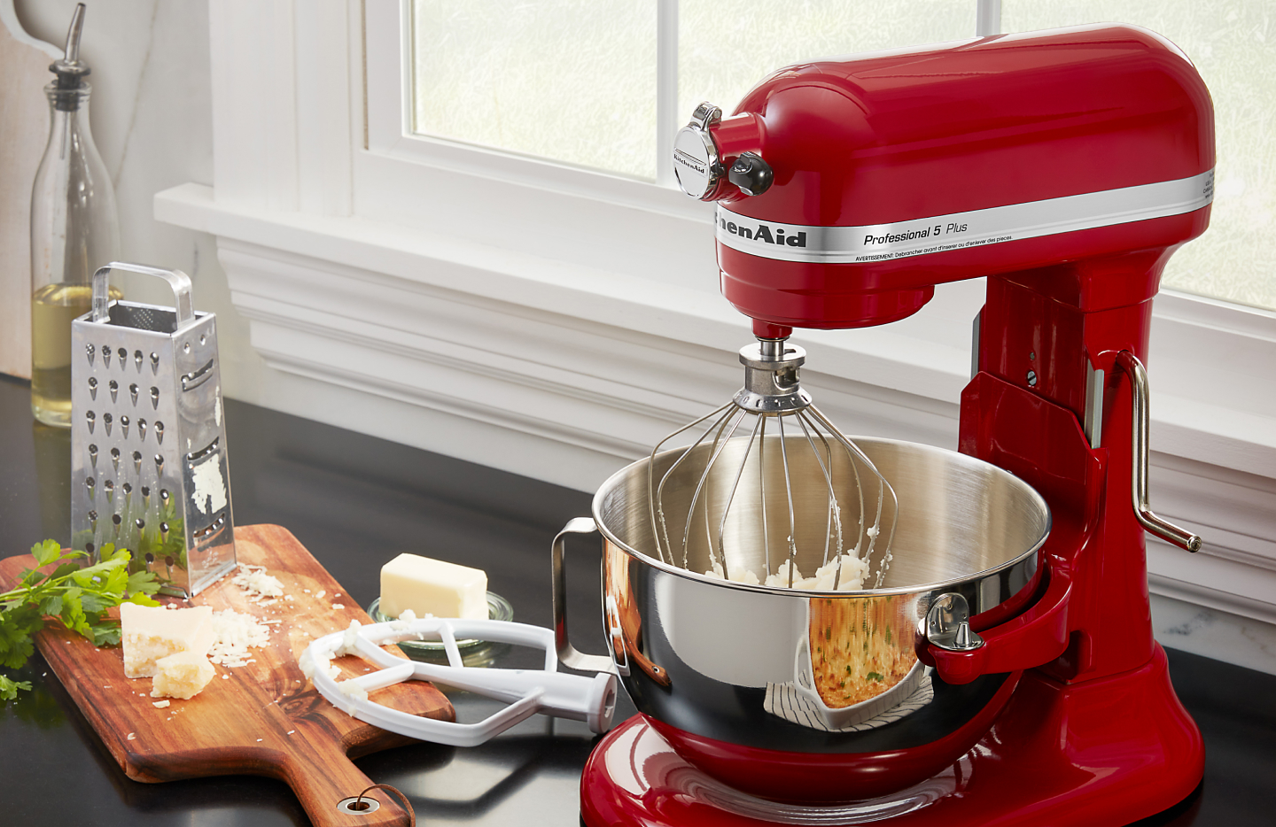 Red KitchenAid® stand mixer next to grated cheese and butter