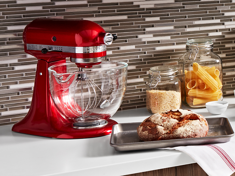 A loaf of bread next to a red KitchenAid® stand mixer with flat beater accessory