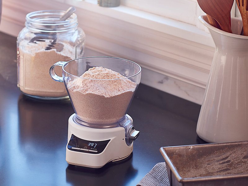 A red KitchenAid® stand mixer amongst a food scale and various baking ingredients