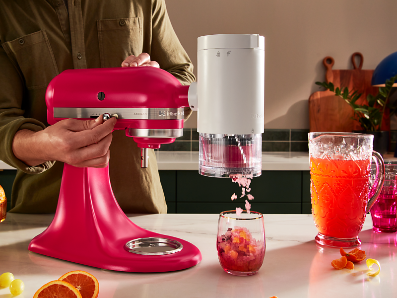 Pink KitchenAid® stand mixer with the KitchenAid®  Shave Ice Attachment shaving flavored ice into drink