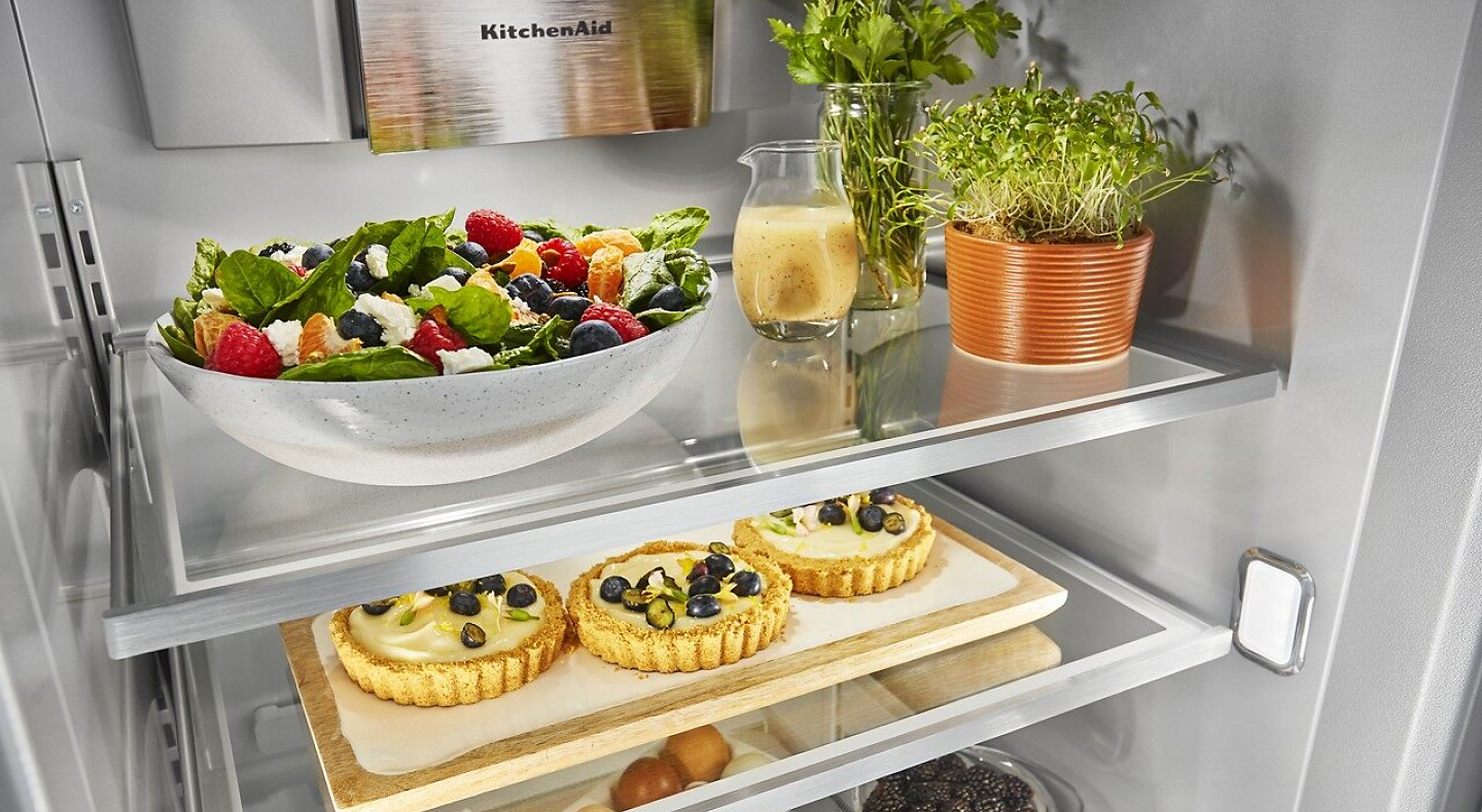 Food platters, herbs and tarts in an open refrigerator