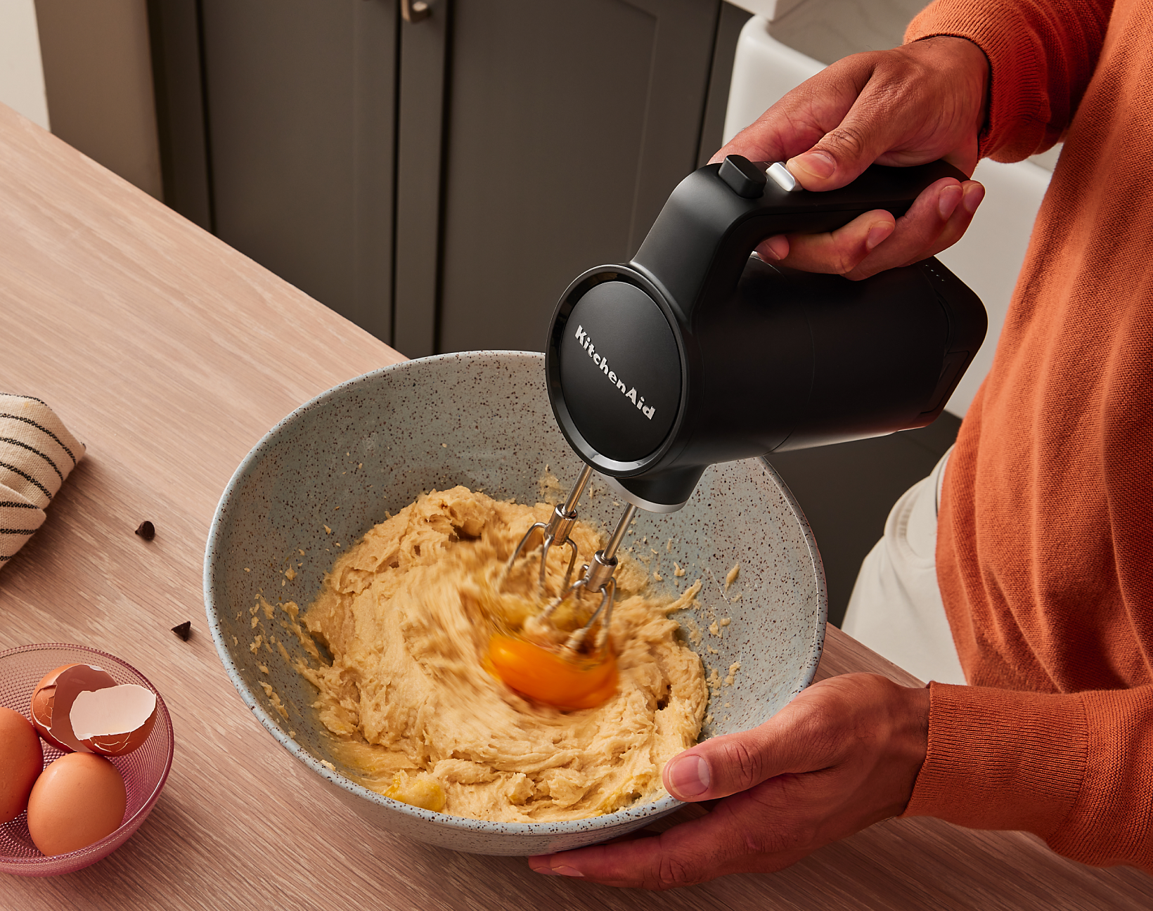 A person using the KitchenAid Go™ Cordless Hand Mixer to beat egg yolks into a dough.