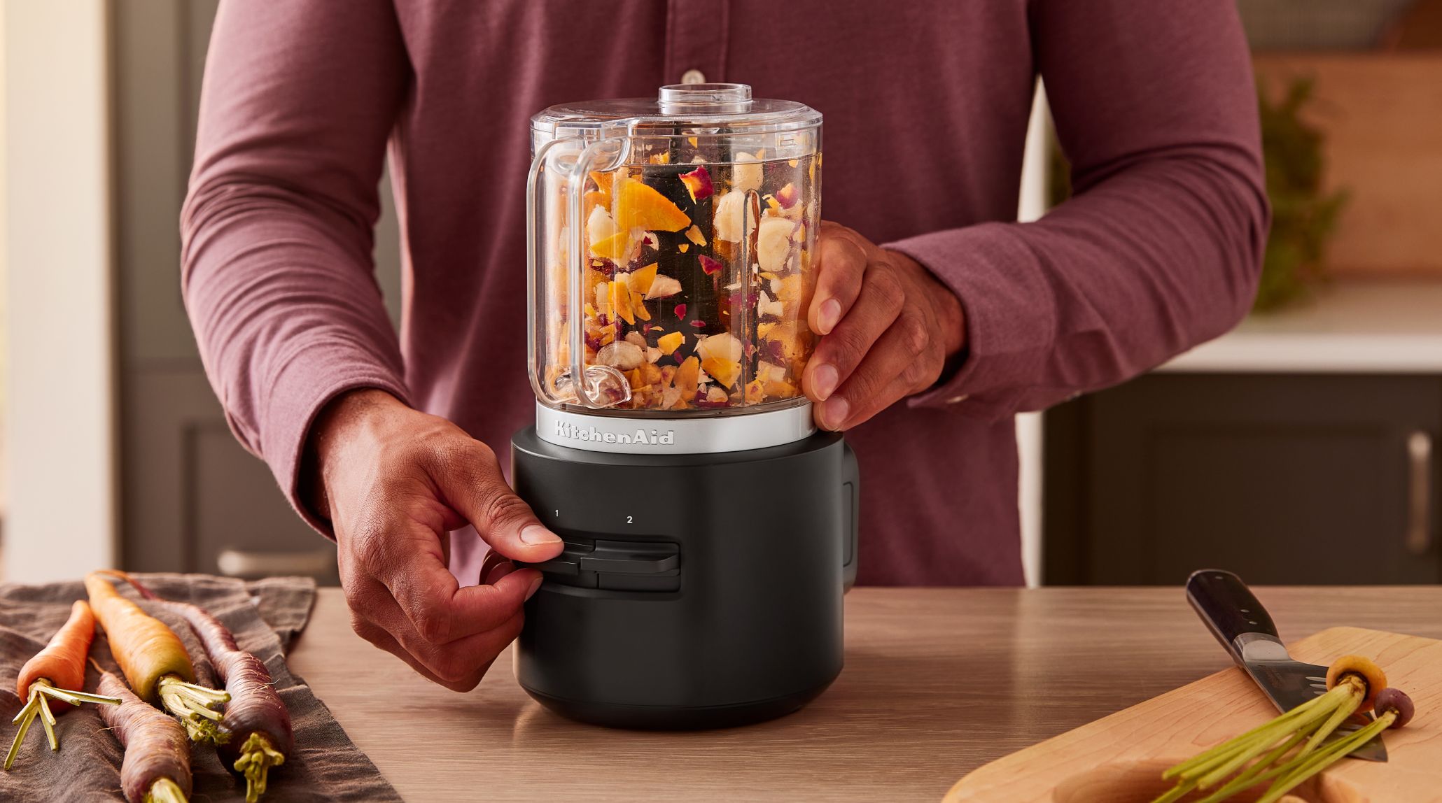 A person operating the KitchenAid Go™ Cordless Food Chopper with vegetables inside.